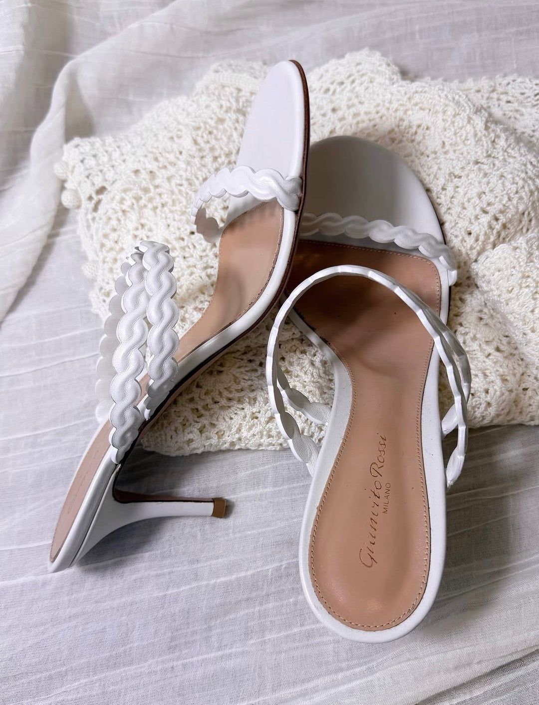 white Gianvito Rossi heeled sandals with braided straps on a white fabric backdrop