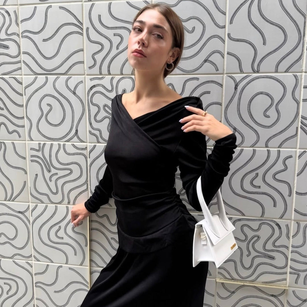 Female model wearing long sleeve v-neck designer dress and posing in front of a tiled wall with wavy lines