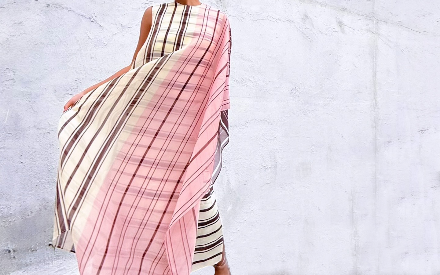 Woman wearing a designer striped dress against a white background