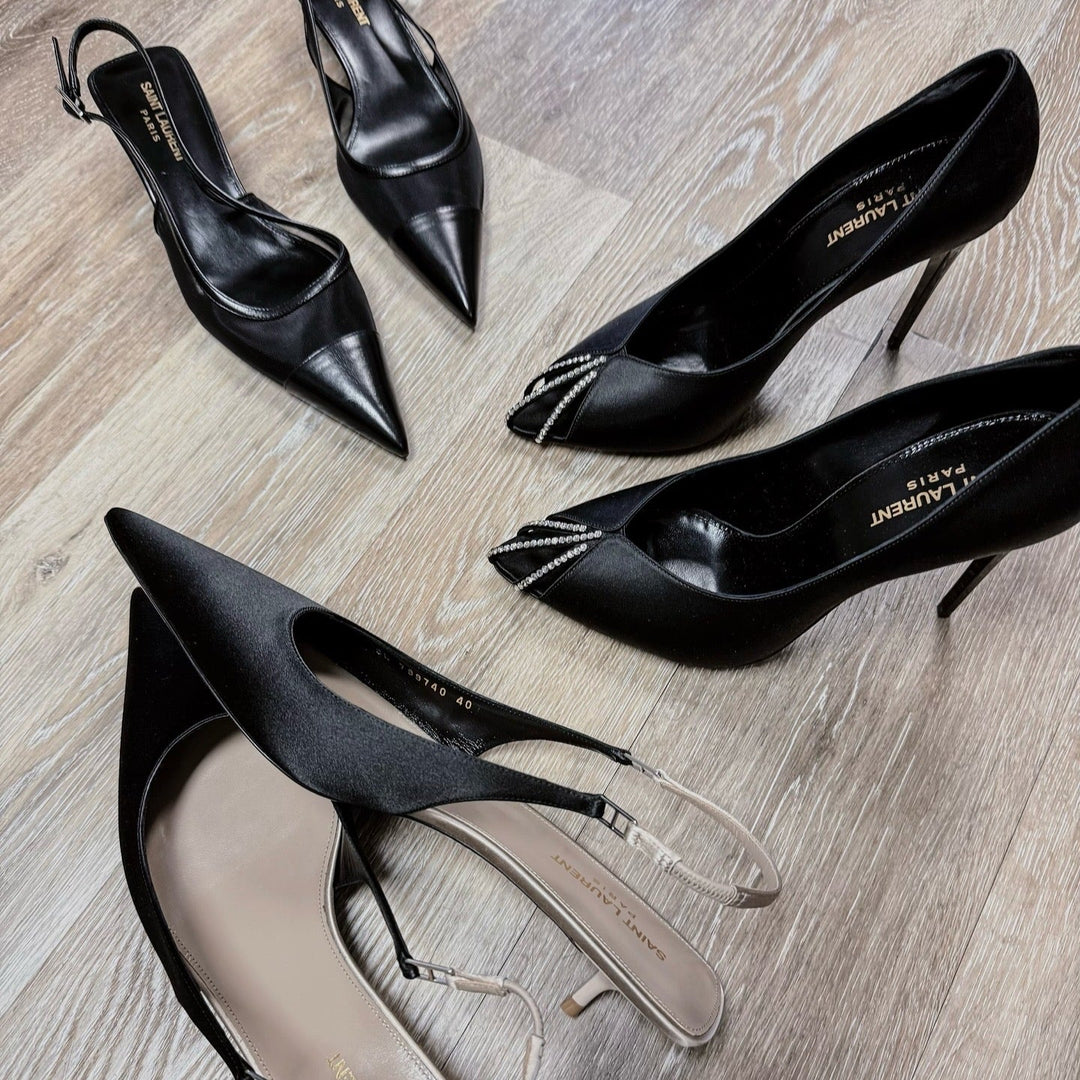 Black high-heeled designer shoes on a wooden floor