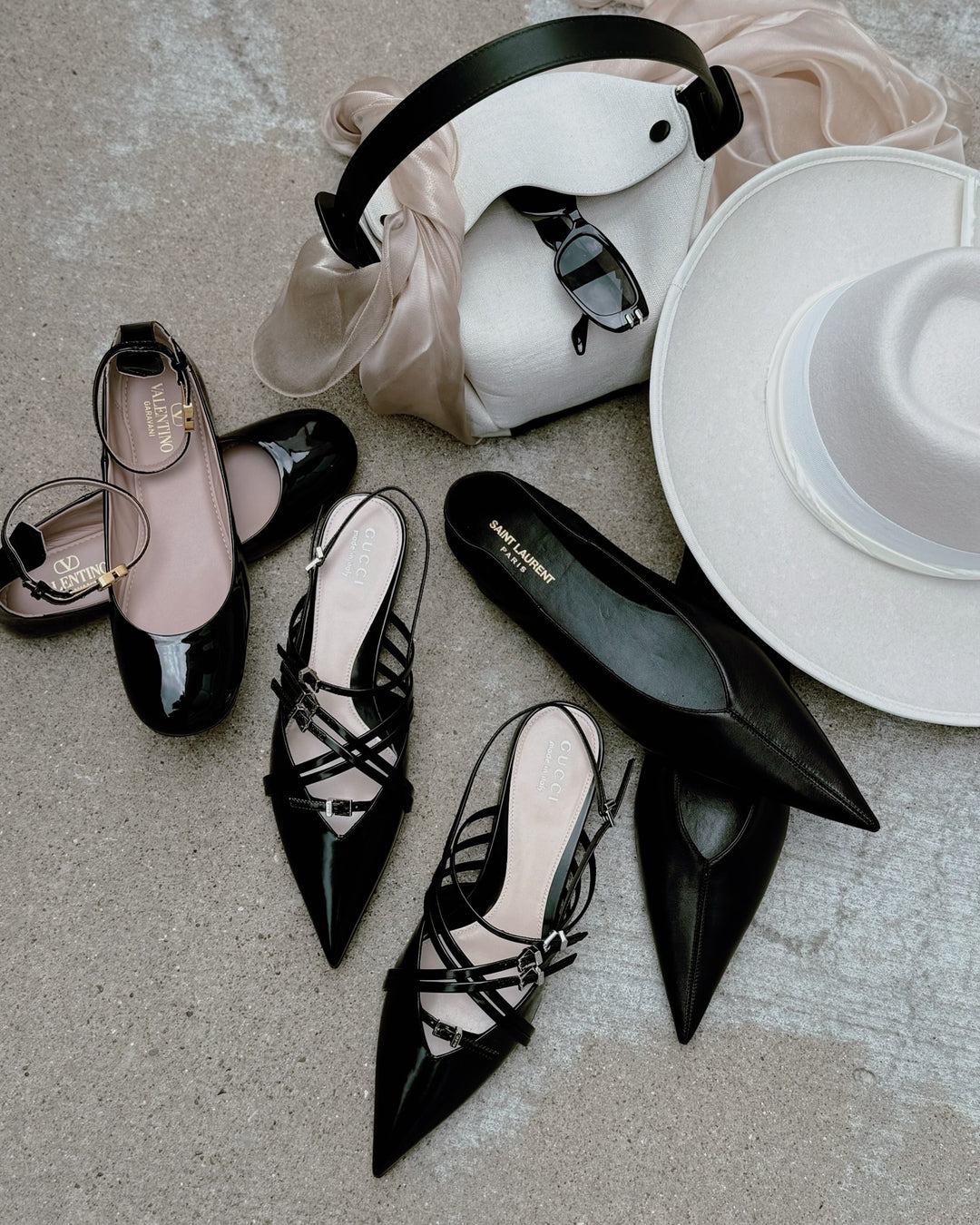 Black high-heeled designer shoes with strappy details on a light gray surface.