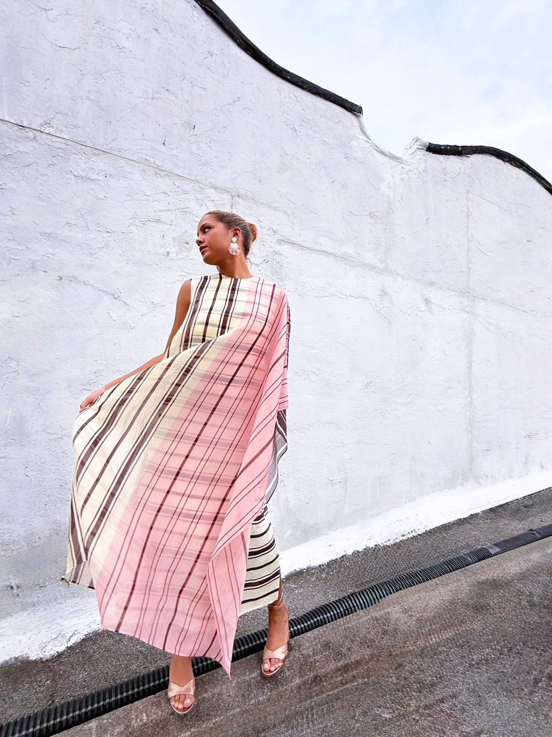 Female model wearing a designer pink plaid dress with a white wall background