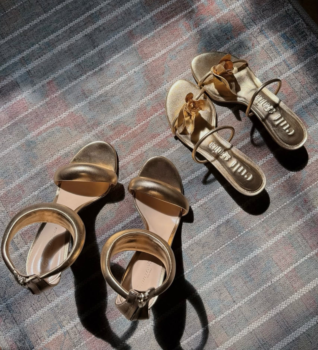Pair of gold high-heeled sandals on a textured surface