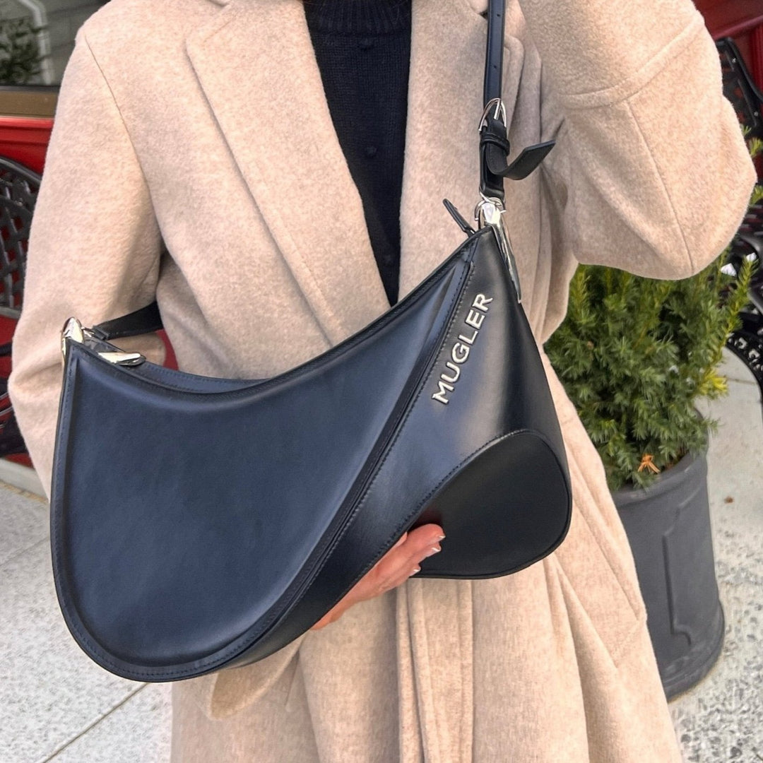 Close up of female model holding black leather Mugler designer handbag